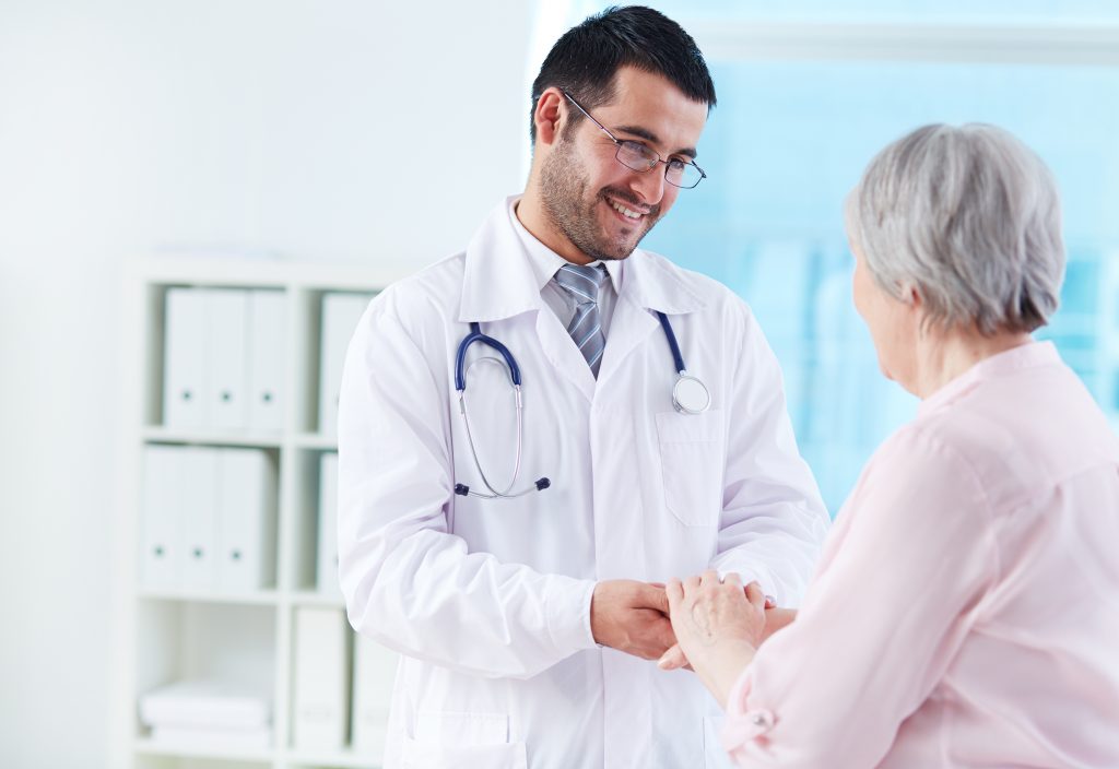 Confident doctor looking at his senior patient while speaking to her