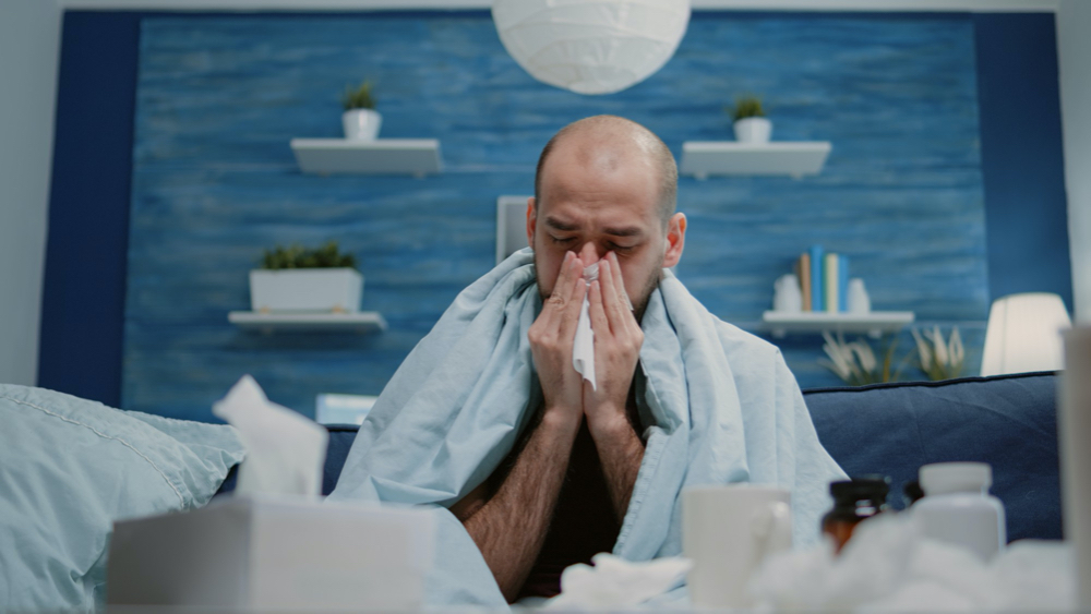 photo close up of man with cold and flu blowing runny nose clogged nose