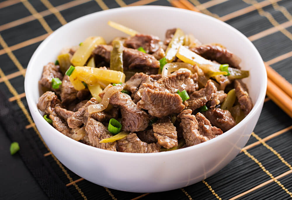 Stew beef, pieces of beef stewed in soy sauce with spices with pickled cucumber in asian style.